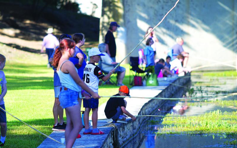 Youth line the creek in W.M. Brook Park trying to catch as many fish as possible during the Spring Ho Kiddie Fishing Derby. HUNTER KING | DISPATCH RECORD