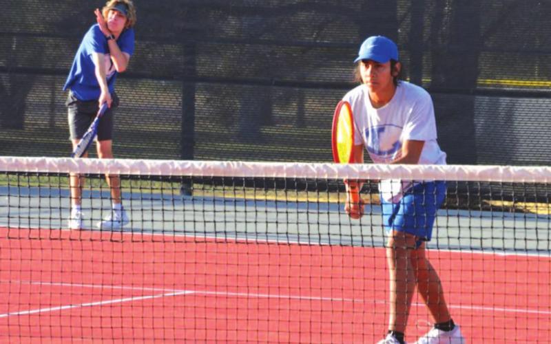 Luke Rogers, left, follows through on a serve as James Vasquez awaits a return in the boys’ regional match. COURTESY PHOTO