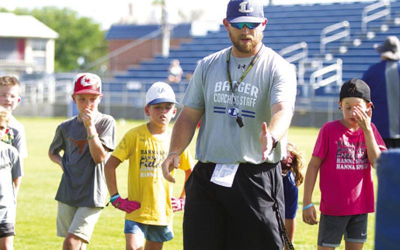 Assistant coach Chance Evans teaches a pass rush drill to campers on Wednesday. HUNTER KING | DISPATCH RECORD