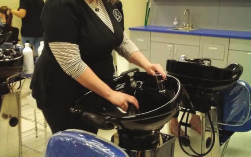 Elizabeth Casper demonstrates use of the shampoo bowls during the salon open house on Dec. 8. VERONICA BUTLER | DISPATCH RECORD