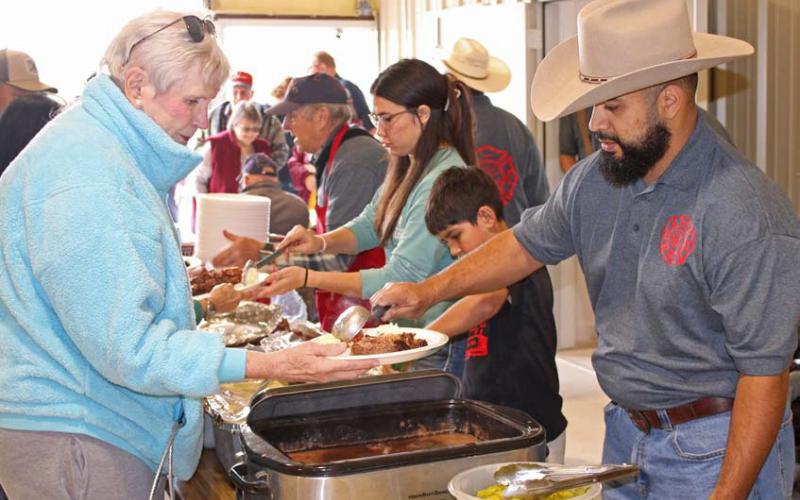 Lometa VFD member Paul Sanchez serves a member of the community during the annual barbecue fundraiser event. Mason hines | Dispatch Record