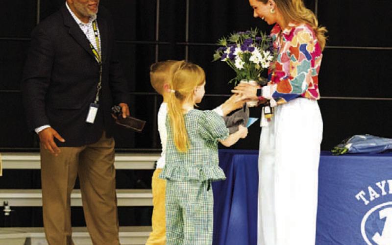 Lauren Robinson receives flowers from her two children as she was awarded Teacher of the Year honors at Taylor Creek Elementary. Principal Mark Sheppard presented the award to the fifth-grade teacher at an assembly earlier this month. HUNTER KING | DISPATCH RECORD