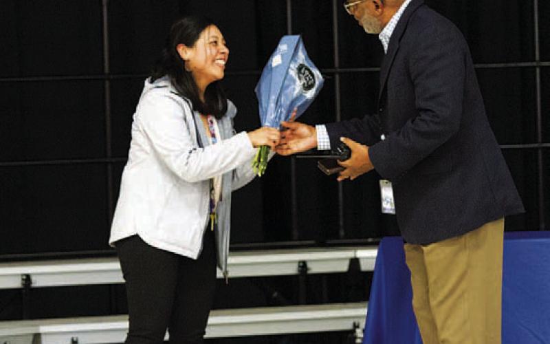 Marisol Zambrano is handed a bouqet of flowers by Sheppard during the assembly. Zambrano was a finalist for the Teacher of the Year recognition at the Taylor Creek campus. HUNTER KING | DISPATCH RECORD