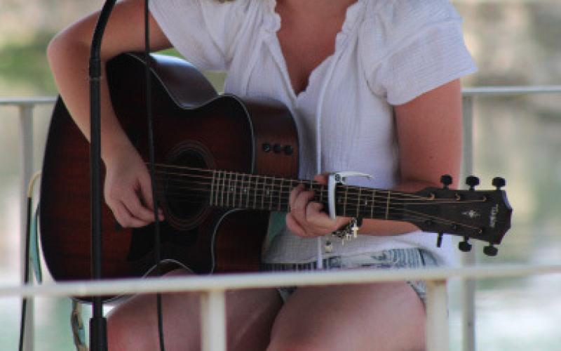 Hometown girls Daelyn Ellis plays her guitar and sings “Those Boots,” written by Lainey Wilson, during music in the park on Wednesday. joycesarah mccabe | dispatch record