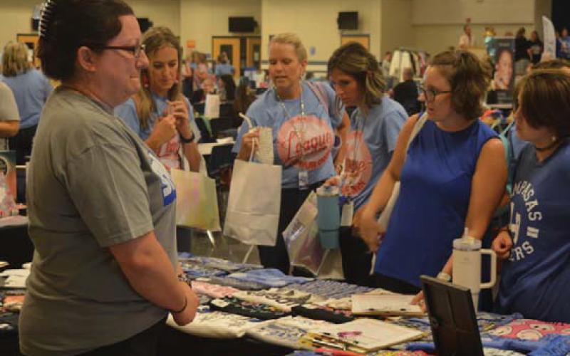 Teachers surround the Graceful Grit Boutique table during Friday’s Back to School Bash in the high school cafeteria. erick mitchell | dispatch record