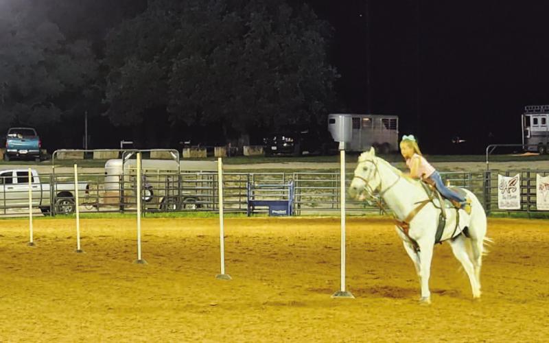 Linden Bumpas and her horse work the poles at the junior rodeo competition. Pole bending is a timed event in which the horse and rider run a weaving path around six poles arranged in a line. COURTESY PHOTO