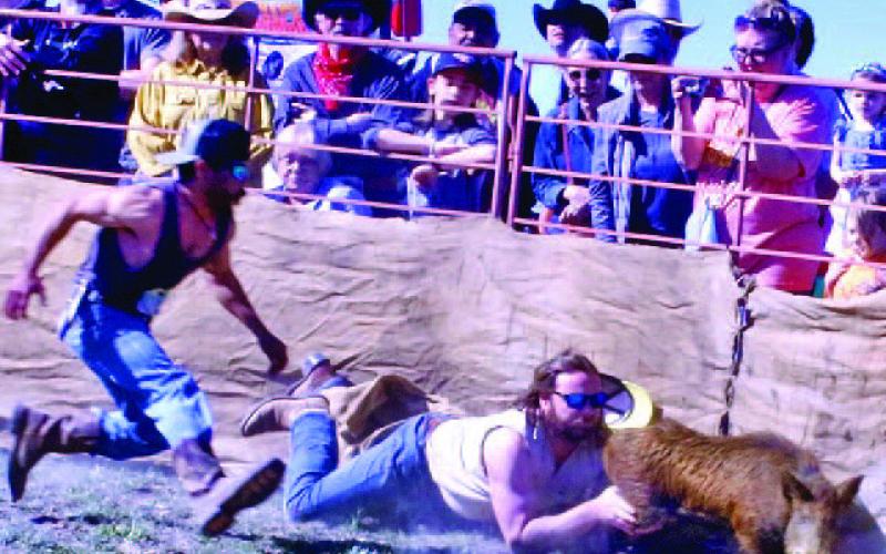 Skeeter Mitchell, left, and Sam Pauly wrestle a hog during the newly introduced “Wild Hog Sacking” event. Pauly and Mitchell finished fourth overall. MASON HINES | DISPATCH RECORD