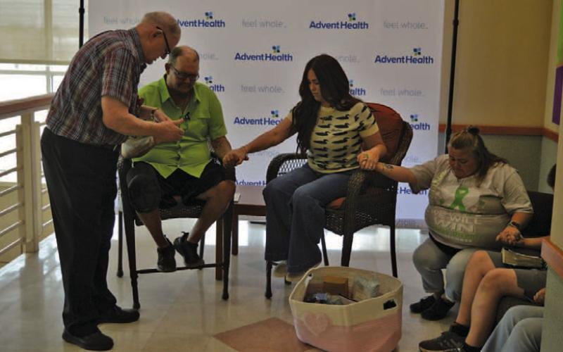 AdventHealth chaplain Jack Gilliland, at left, prays with Michael Miller, Brandy Watkins and Amy Miller in advance of next week’s transplant surgery. ERICK MITCHELL | DISPATCH RECORD