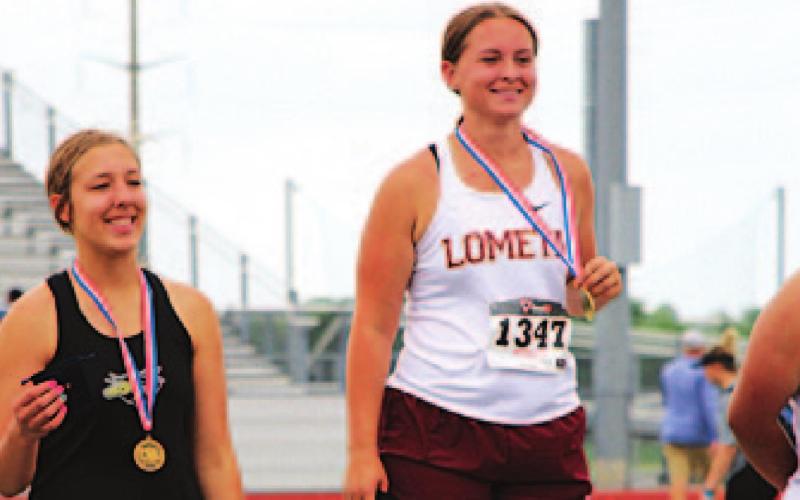 Sierra Tower stands atop the podium at the regional track meet after winning the discus event. JESSICA MALDONADO | DISPATCH RECORD
