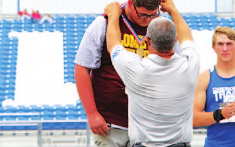 Copeland Brister has a medal placed around his neck after his third-place finish at the regional track meet. JESSICA MALDONADO | DISPATCH RECORD