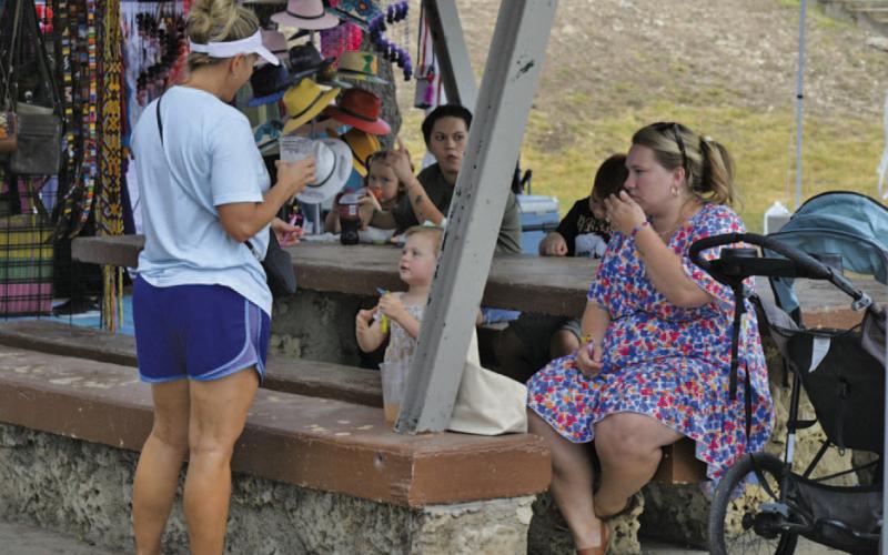 Lampasas residents Amy Vann, at left, and Leyna Brewer and her daughter enjoy concessions and shopping among the park vendors while out for Spring Ho festivities. ERICK MITCHELL | DISPATCH RECORD
