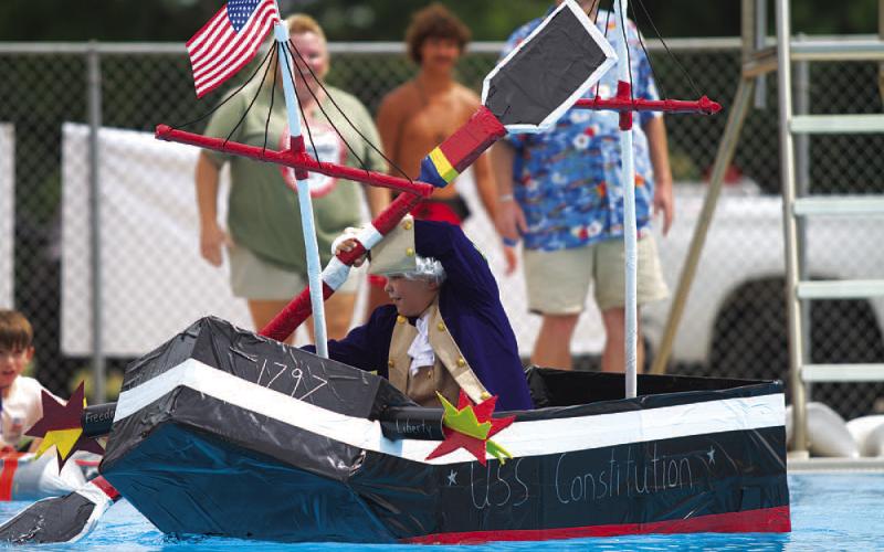 Case Jones rows the U.S.S Constitution across the Hanna Springs Swimming Pool during the Cardboard Regatta event on Saturday. HUNTER KING | DISPATCH RECORD