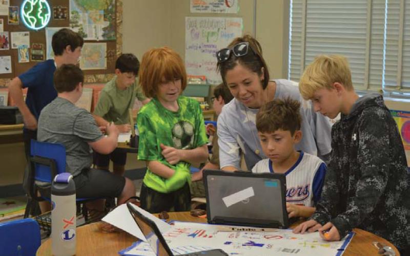 Sixth-grade social studies teacher Kamaria Lambert helps students make the finishing touches on their Bill of Rights poster. Erick Mitchell | Dispatch Record