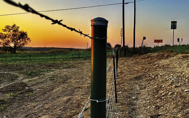 As the sun rises over Lampasas County, a new fence surrounds a vast hayfield, standing strong against the morning light. The sturdy metal posts and taut wire symbolize the resilience and determination of the agricultural community to rebuild JOYCESARAH MCCABE | DISPATCH RECORD