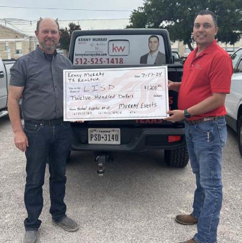 courtesy photo At left, Lometa ISD Superintendent Rob Moore and Kenny Murray showcase a $1,200 donation for school supplies to assist the district. Funds come from the Third Annual KM Scramble held earlier this summer.