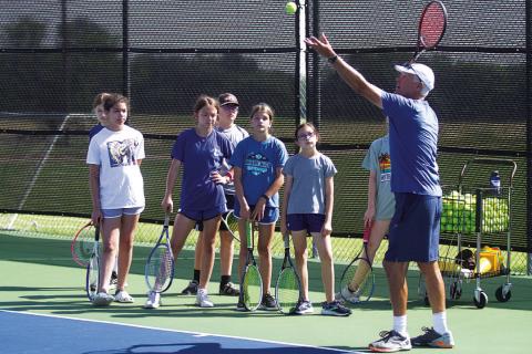 Kenneth Peiser shows young campers some serving tips at camp on Friday. HUNTER KING | DISPATCH RECORD