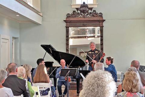 Bruce Williams introduces fellow musicians Patrice Calixte, Douglas Harvey and Dr. Stephen Redfield as they prepare to perform “Quartets at the Keystone” for the audience at the Keystone Star Hotel ballroom during last year’s Lampasas Chamber Music Festival in June. file photo