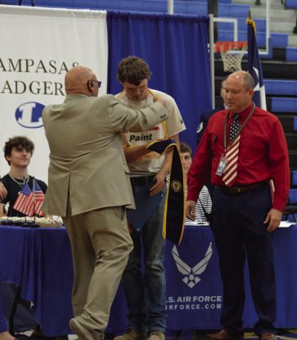 Ethan Walker receives a graduation cord from Assistant Principal Ryan Race to signify the senior’s commitment to the Navy, as Principal Paul Weinheimer looks on. Walker was one of 11 students recognized during Monday’s Armed Forces signing ceremony at Lampasas High School.
