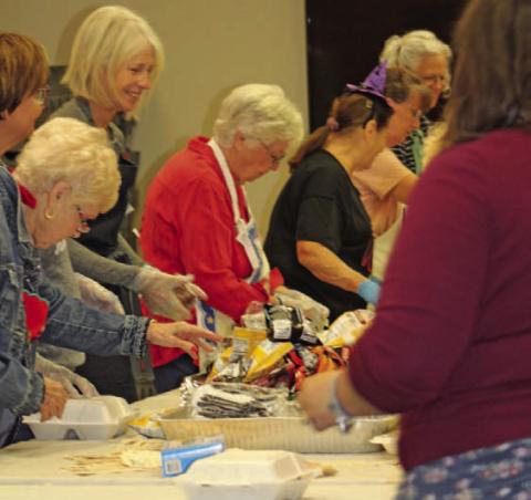Lampasas Public Library staff, board members and volunteers stand shoulder to shoulder fixing lunch plates on Monday for the library’s biggest fundraiser of the year. All proceeds from the BBQ for Books event go toward the purchase of large-print books, for community programs and needed equipment. JOYCESARAH MCCABE | DISPATCH RECORD