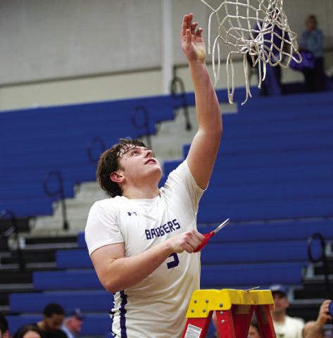 Aidan Nuckles reaches up to cut down the net as the Badgers celebrate their district title. HUNTER KING | DISPATCH RECORD