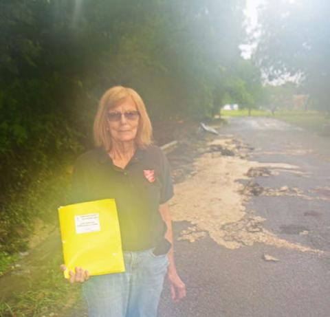 Dorothy Person, a local Salvation Army volunteer, pauses for a photo in front of the flood damages on Avenue H last month. COURTESY PHOTO