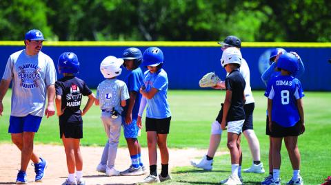 Assistant coach Jaden Napolez, left, talks to some campers about base running this week. HUNTER KING | DISPATCH RECORD