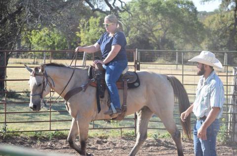 U.S. Armed Forces veteran Krystal Ybarra, a Camp Cowboy program participant, rides “CD” around an arena under the supervision of Lane Robison, program director. Alexandria Randolph | dispatch record