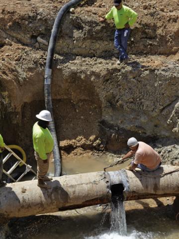 KWSC employees work to repair the leak in the transmission line on Friday afternoon. ERICK MITCHELL | DISPATCH RECORD