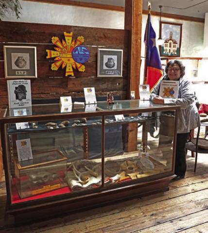 Dorinda Barrett holds the coloring book she wrote and illustrated as she poses next to the museum display case. JOYCESARAH MCCABE | DISPATCH RECORD