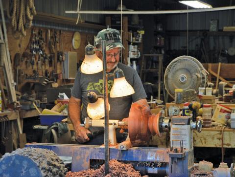 Gene Isenhour looks at a wooden bowl along the lathe he uses to shape his bowls and candle holders. This year alone, Isenhour has made 125 wooden bowls. erick mitchell | dispatch record