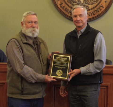Precinct 3 Commissioner Lewis Bridges, left, accepts a plaque from County Judge Randy Hoyer to commemorate Bridges’ service to the county. His term as commissioner will conclude at the end of the month. ERICK MITCHELL | DISPATCH RECORD