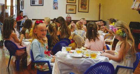 At left, Reagan Groves gives the camera a smile while her fellow Teddy Bear Tea Party attendees stay locked into storytime. ERICK MITCHELL | DISPATCH RECORD