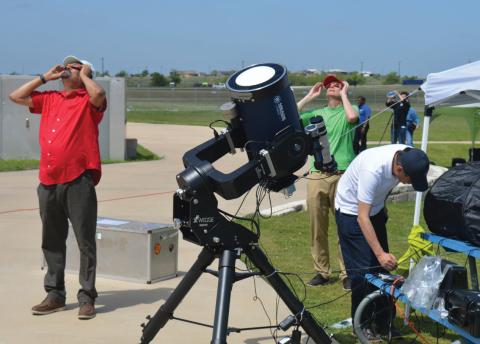 At left, NASA’s Dr. Natchimuthuk Gopalswamy views the partial phase of the eclipse through solar glasses along with other members participating in NASA’s research station set up at the 580 Sports Park on Monday. ERICK MITCHELL | DISPATCH RECORD