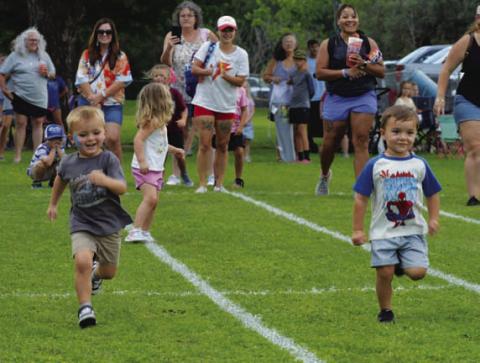 At left, Walker Cook and Theo Ray race to the finish line during last Friday’s Kids’ Day relay races. ERICK MITCHELL | DISPATCH RECORD