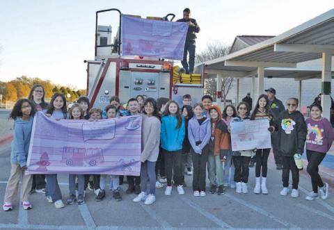 Erick mitchell | dispatch record Hanna Springs Elementary students in Mrs. White’s fifth-grade homeroom class stand in front of the Lampasas Fire Department engine as they hoist the winning flag on Tuesday morning.