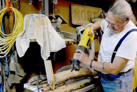Allen Leske cuts a branch, preparing to assemble it into a cross. MADELEINE MILLER | DISPATCH RECORD