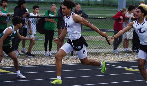 HUNTER KING | DISPATCH RECORD Ty Johnson receives the baton from Jaden McElwain during the 4x200-meter relay last Thursday.