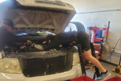 Nathan Abken, at right, leans over the hood of a pickup as he works on an engine as part of his training this spring in the Lampasas High School Auto Tech II class. FILE PHOTO