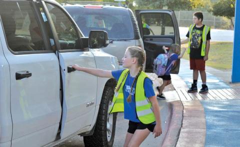 First-year World Changer McKaylynn McKinnon prepares to open the door for a fellow student during morning drop-off patrol. erick mitchell | dispatch record