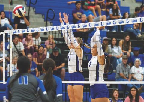 HUNTER KING | DISPATCH RECORD Scout Barton, left, and Madison Magilke leap for a block at the volleyball team’s home opener.