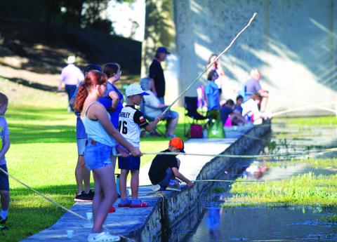 Youth line the creek in W.M. Brook Park trying to catch as many fish as possible during the Spring Ho Kiddie Fishing Derby. HUNTER KING | DISPATCH RECORD