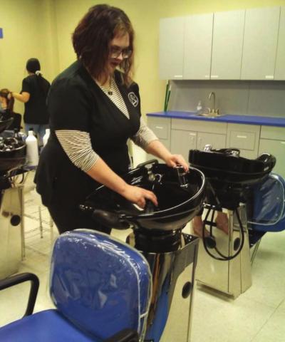 Elizabeth Casper demonstrates use of the shampoo bowls during the salon open house on Dec. 8. VERONICA BUTLER | DISPATCH RECORD