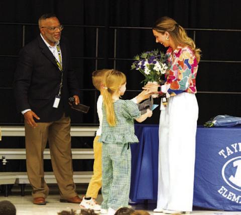 Lauren Robinson receives flowers from her two children as she was awarded Teacher of the Year honors at Taylor Creek Elementary. Principal Mark Sheppard presented the award to the fifth-grade teacher at an assembly earlier this month. HUNTER KING | DISPATCH RECORD
