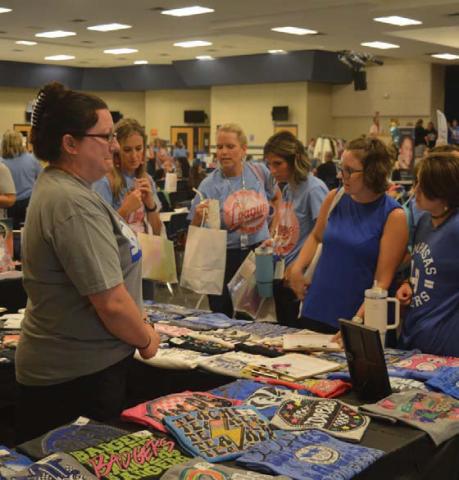 Teachers surround the Graceful Grit Boutique table during Friday’s Back to School Bash in the high school cafeteria. erick mitchell | dispatch record