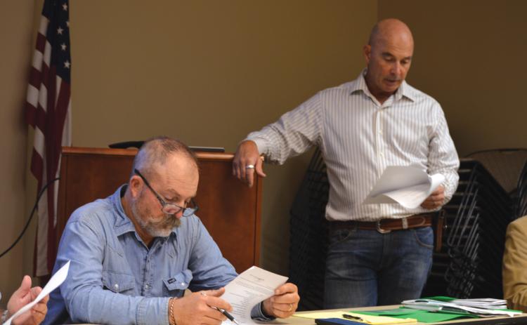 At left, Saratoga UWCD Board President Paul Cline reviews his notes as Director Stan Wilson discusses a change to the district’s fees for non-exempt wells. ERICK MITCHELL | DISPATCH RECORD