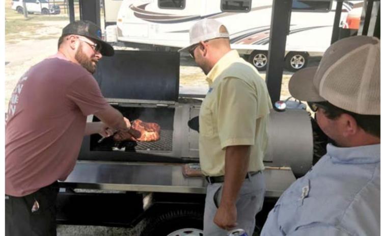 Teammates TJ Wright, at left, Brodi Bocnegra and Wes Canales prepare their meat in last year’s LTX BBQ Fest competition. FILE PHOTO