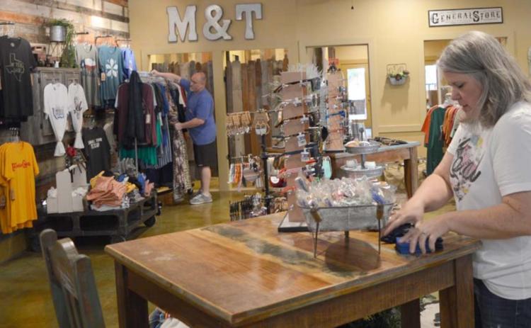Jo Williams, foreground, and John Williams stock merchandise in the Merk &amp; Tilley’s boutique on the downtown square. Since May, when COVID-19 restrictions eased and the business was allowed to reopen, Merk &amp; Tilley’s revenue has grown by at least 25% each month, John Williams said. FILE PHOTO