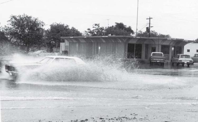 A car passes through the flooded roadway at Key Avenue and Seventh Street. A low-water crossing was created across Key Avenue at this intersection in the 1950s to channel runoff from the west side of the roadway. lampasas dispatch record, April 1971