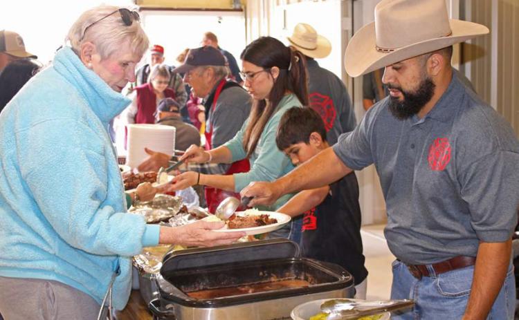 Lometa VFD member Paul Sanchez serves a member of the community during the annual barbecue fundraiser event. Mason hines | Dispatch Record