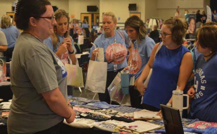 Teachers surround the Graceful Grit Boutique table during Friday’s Back to School Bash in the high school cafeteria. erick mitchell | dispatch record